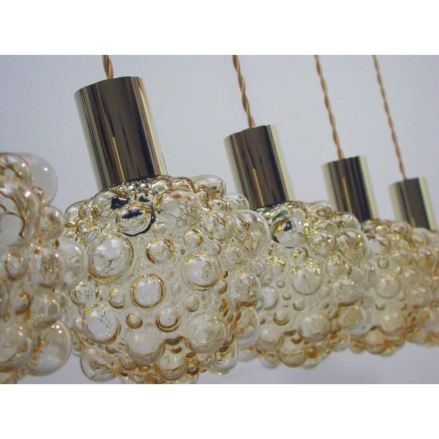 This Space Age pendant lamp was designed and manufactured in Germany during the 1960s. It is made of amber bubble glass...