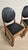 A set of four vintage wooden dining chairs featuring warm-toned wooden frames and distinctive rounded black upholstered...