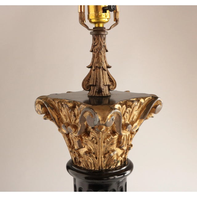 Glossy black column with gilded capital decorated with acanthus leaves and scrolls. Mounted on an acrylic base, this lamp...