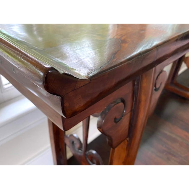A large and graceful Chinese altar console table with an inverted flange top and straight legs connected by pierced carved...