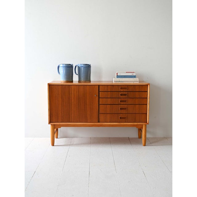 Vintage teak sideboard with oak legs and profiles. Equipped with a hinged door and five drawers. The sideboard has a...