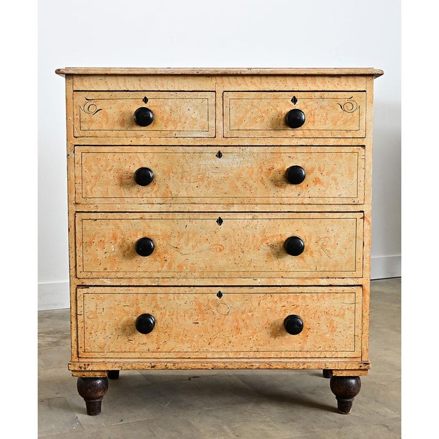 This English chest of drawers from the 19th Century is built from solid pine with a faux bois finish to imitate birdseye...