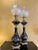 Pair of oil lamps converted to electricity, with black ceramic stems decorated in polychrome with peacocks and flowering...