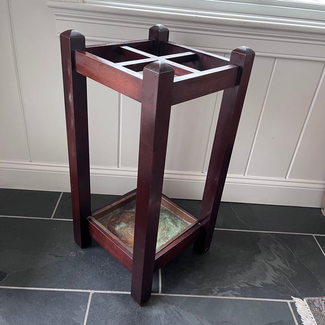 A handsome antique umbrella stand crafted from richly toned wood, featuring a sturdy open-frame design with a crossed...