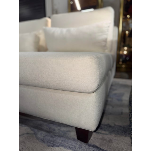 White fabric customer loveseat with a clean, modern look that brightens any living space. The piece features comfortable...