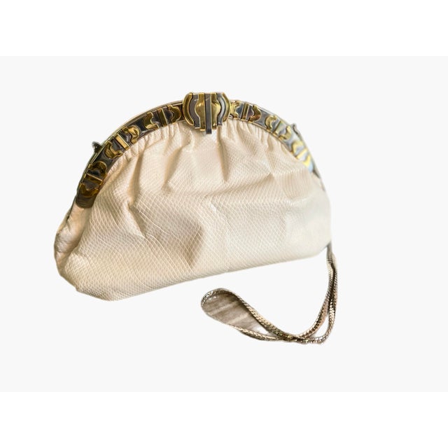 Ivory toned karung snake clutch in ample proportions.. Fantastic two toned frame in silver and gold geometric deign....