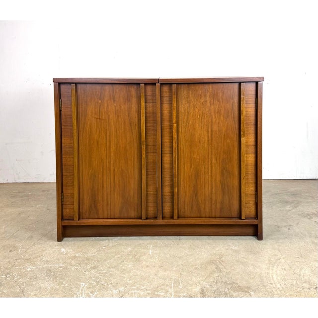 A beautiful mid century modern walnut media / audio cabinet with top compartment for a turntable, left side compartment...