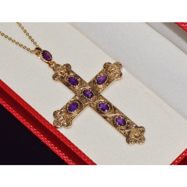This is a magnificent estate cross pendant crafted in solid 18K yellow gold, featuring seven natural oval-cut amethysts...