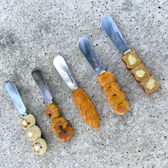 A charming and whimsical set of vintage butter knives featuring detailed bread-inspired handles, each uniquely designed to...