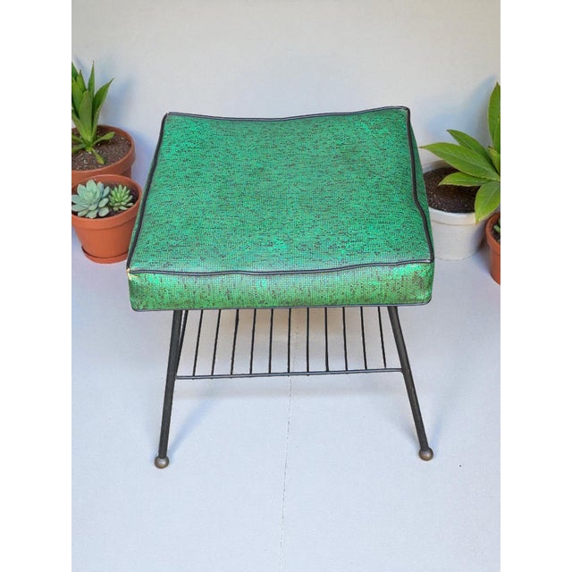 This Retro 1950s Mid-Century footstool with a magazine rack features a green vinyl top and a metal base, making it a...
