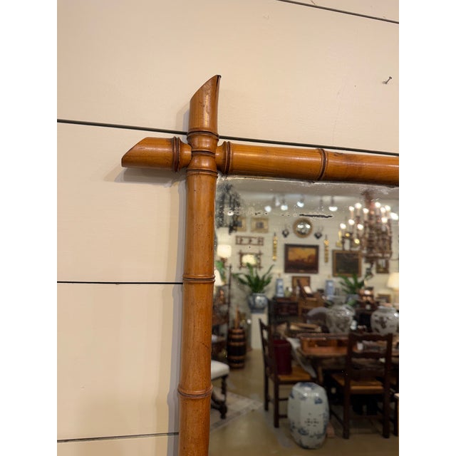 This is a French antique faux-bamboo wall mirror with a hand-carved wood frame. The frame is wood that has been shaped and...