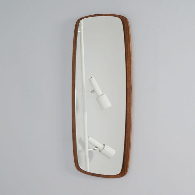 Danish wall mirror in teak from the 60s with a slim, organically shaped edge and rounded corners. The soft lines, warm...