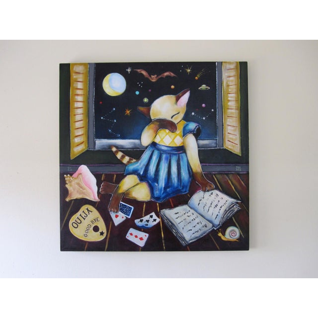 In "Bedtime Story," a whimsical scene unfolds as a cat, dressed in a blue nightgown, sits by an open window, gazing...