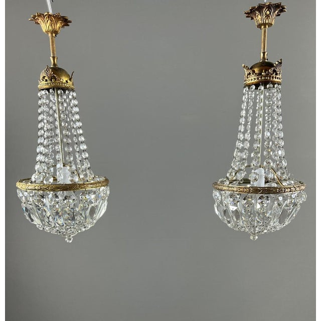 An elegant pair of bronze and cut crystal pendant lights, dating from the late 19th or early 20th century. Each light...