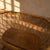 A vintage rattan baby bassinet from the 1970s, designed with an oval wicker basket and a low wooden stand. The decorative...