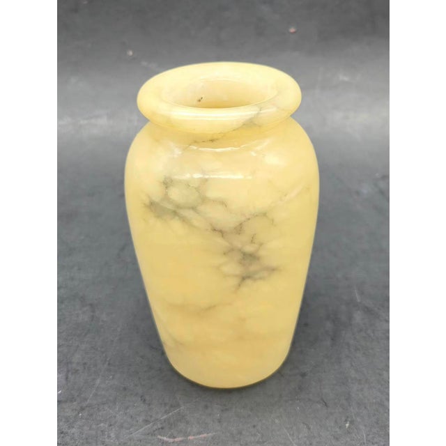 This item appears to be a small, vintage hand-carved alabaster vase featuring a creamy honey base with distinctive grey...