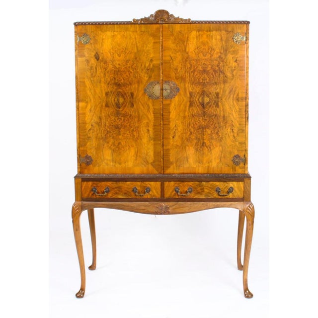 This is a fantastic vintage Queen Anne Revival burr walnut cocktail cabinet with wonderful hand carved decoration dating...