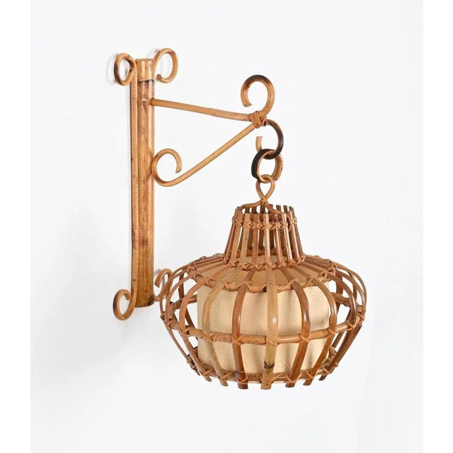 Stunning French Riviera style wall lamp fully made in curved rattan, hand-woven wicker and cane with a parchment shade....