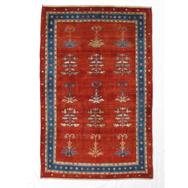 Vintage Hand-knotted Persian Lori Gabbeh rug featuring a rich red field with a repeating arrangement of stylized tree and...