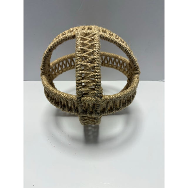 A sculptural hand-wrapped jute rope orb featuring an open lattice weave and reinforced cross-band construction. Crafted in...