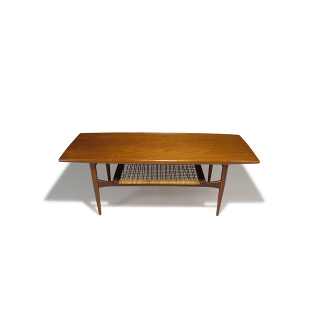 Beautifully crafted, this mid-century Danish teak coffee table features a sculptural raised-edge surface and a woven caned...