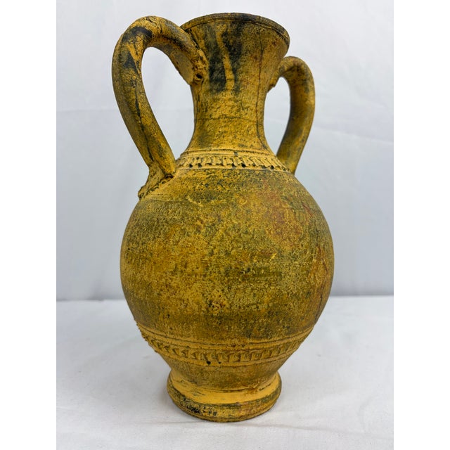 A decorative terracotta amphora urn featuring a textured Scavo-style finish with mottled yellow and brown tones. The...