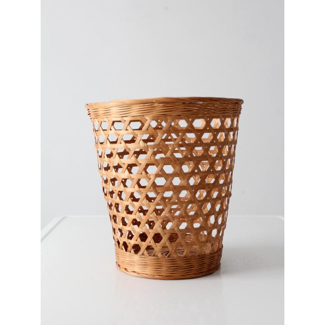 Vintage open weave wicker basket featuring a tapered silhouette, airy lattice weave, and warm natural finish. Its...