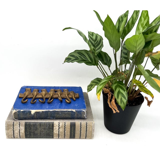 Delightfully whimsical vintage brass wall hook featuring a row of stylized cats sitting shoulder to shoulder, all facing...