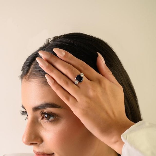 This elegant Art Deco-style three-stone ring features 1 octagon cut blue sapphire totaling 3.33 carats, set in rich 18K...