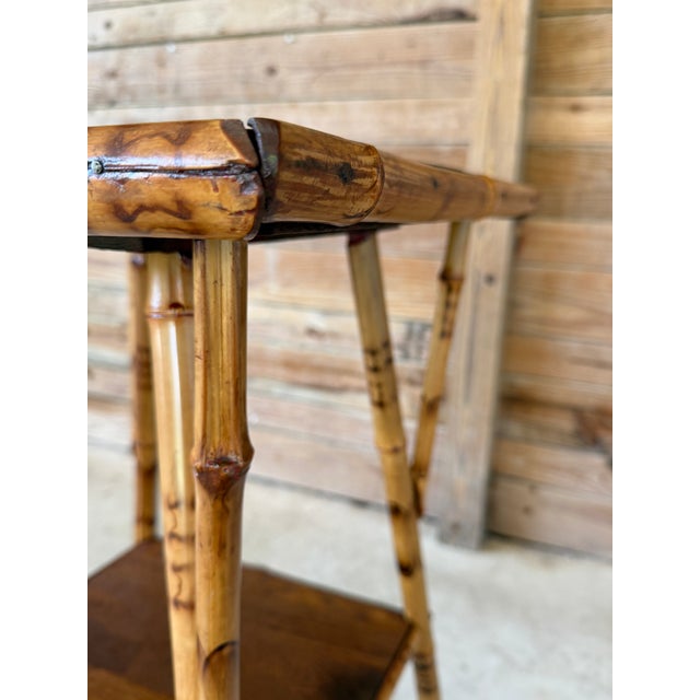 A wonderfully character-filled antique scorched bamboo side table featuring a square wood top, lower shelf and splayed...