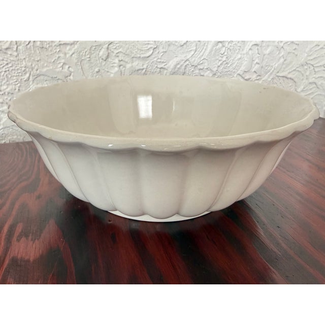 White glazed English ironstone bowl. Deep fluted panels run around the outside. The rim is softly scalloped. It works as a...