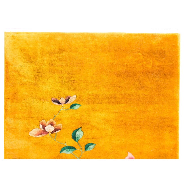 A bold early 20th Century Chinese Art Deco rug with a brilliant gold field with a large multi-colored peony cluster in one...