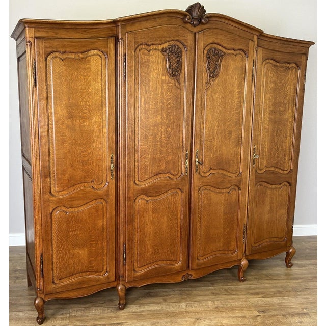A beautiful Vintage French Louis wardrobe crafted from oak, featuring an elegant four door design with decorative carved...