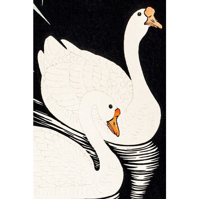 A serene study of two white Chinese geese gliding through dark reflective waters beneath graceful reeds. Reproduced from a...
