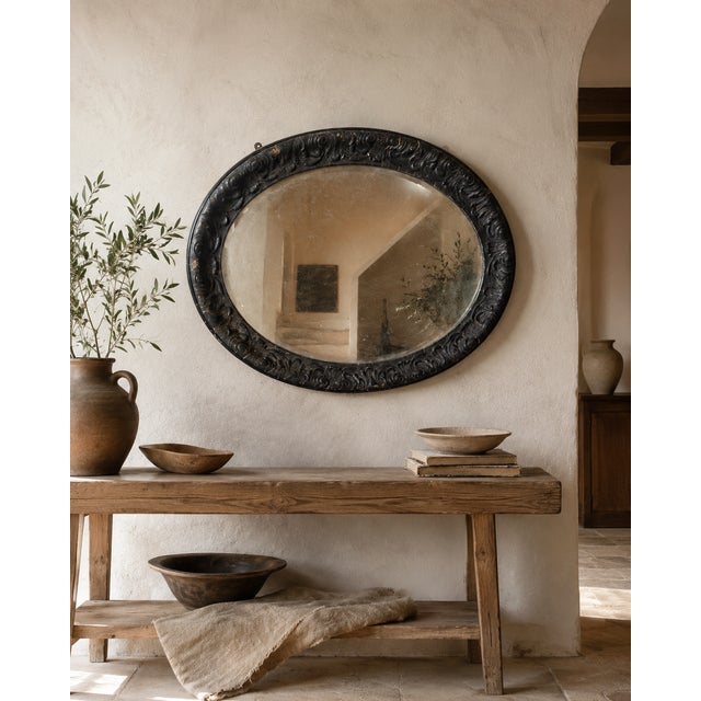 A striking late 19th-century oval wall mirror with a richly decorated ebonised frame and beautifully aged bevelled mirror...