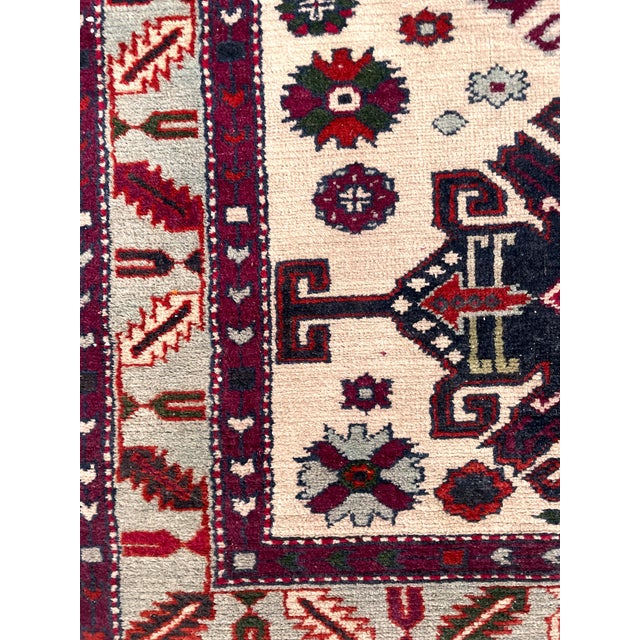 A beautiful hand-knotted Kazak style rug featuring a striking geometric tribal design and a refined ivory field adorned...