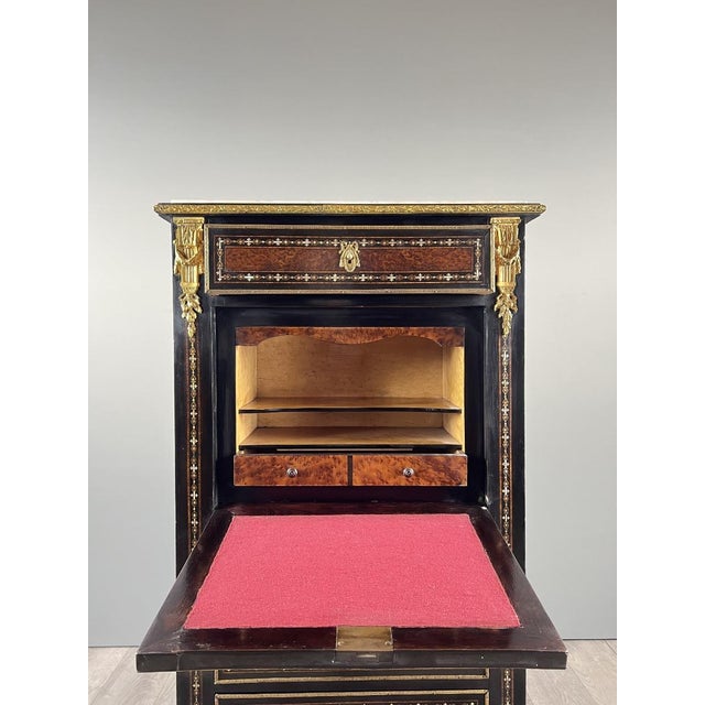 An elegant antique secretary desk from the Napoleon III period, crafted from ebonized wood and richly decorated with...