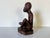 This exquisite vintage African art piece showcases a hand-carved wooden figure, elegantly depicting a seated musician. The...