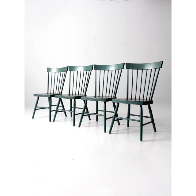 A set of four vintage pine dining chairs, each finished in a softly weathered jade green that allows the natural knots and...