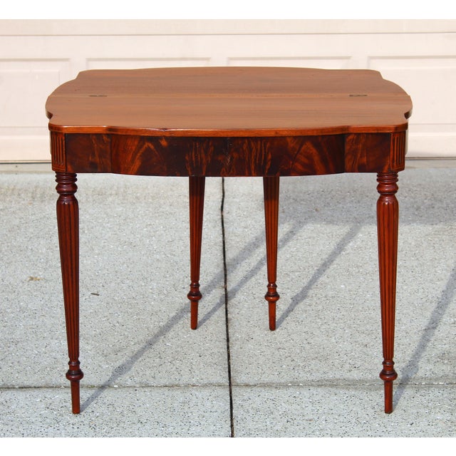 Elegant early 20th-century flame mahogany gate-leg table that doubles as a folding card table or antique writing desk. A...
