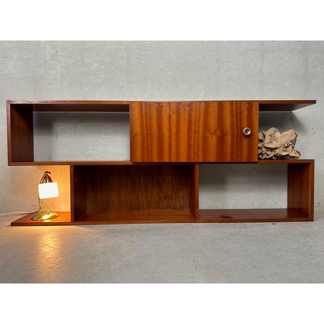Vintage wall unit in teak veneer. Asymmetrical design with partially open and closed shelves. One storage compartment...