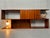 Vintage wall unit in teak veneer. Asymmetrical design with partially open and closed shelves. One storage compartment...