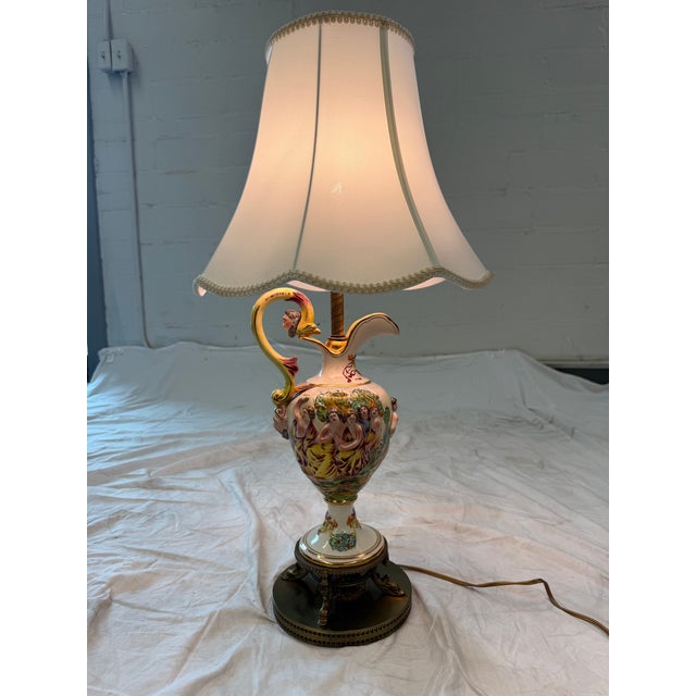 A striking pair of Italian Capodimonte-style table lamps featuring hand-painted porcelain urn bodies decorated with...