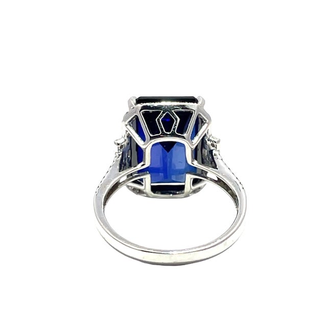 Elegant 14k white gold ring featuring a vivid emerald-cut blue sapphire accented with sparkling diamonds along the...