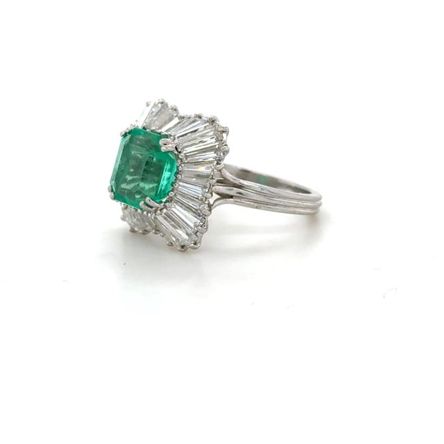 This fun cocktail ring boasts a treated emerald cut emerald weighing approximately 3.10 carats surrounded by 28 tapered...