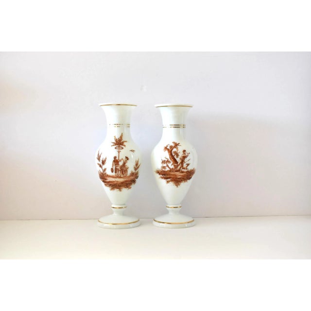A pair of antique 19th-century French white opaline glass baluster vases, hand-painted with brown sepia grisaille...