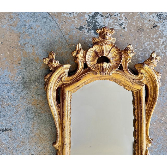 A finely crafted pair of Italian giltwood wall mirrors in the Rococo taste, after Borghese. Each is beautifully carved...
