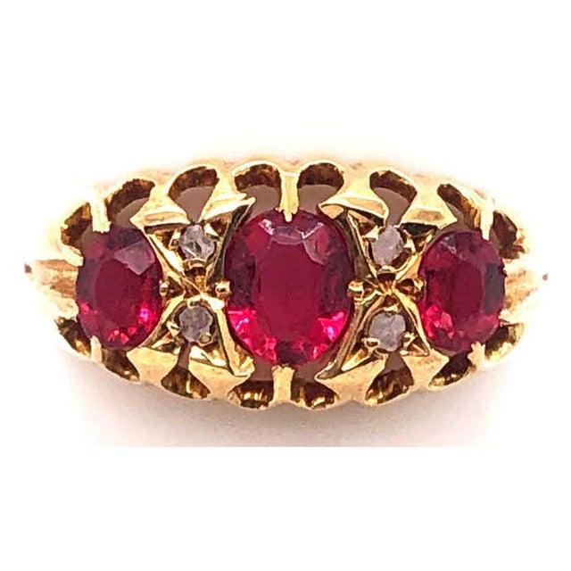 18 Karat Yellow Gold Three Stone Ruby Ring With Diamond Accents 0.04 total diamond weight. Size 5.5 2.94 grams total weight.