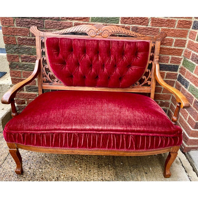 It features rich wine-colored velvet upholstery and ornate etched wood scrollwork with floral detail. It was refinished by...