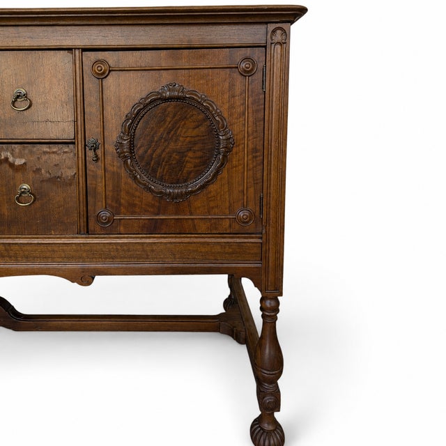 An imposing antique sideboard in the Jacobean Revival tradition, combining richly figured wood surfaces with strong...